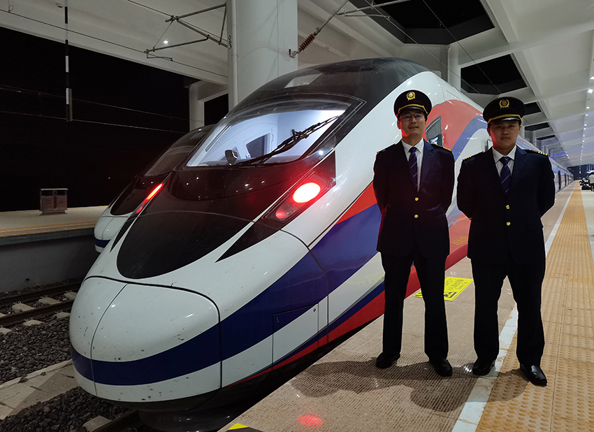 劉銀能（右一）與中國師父鄔俊鴻在動車組前合影。受訪者供圖